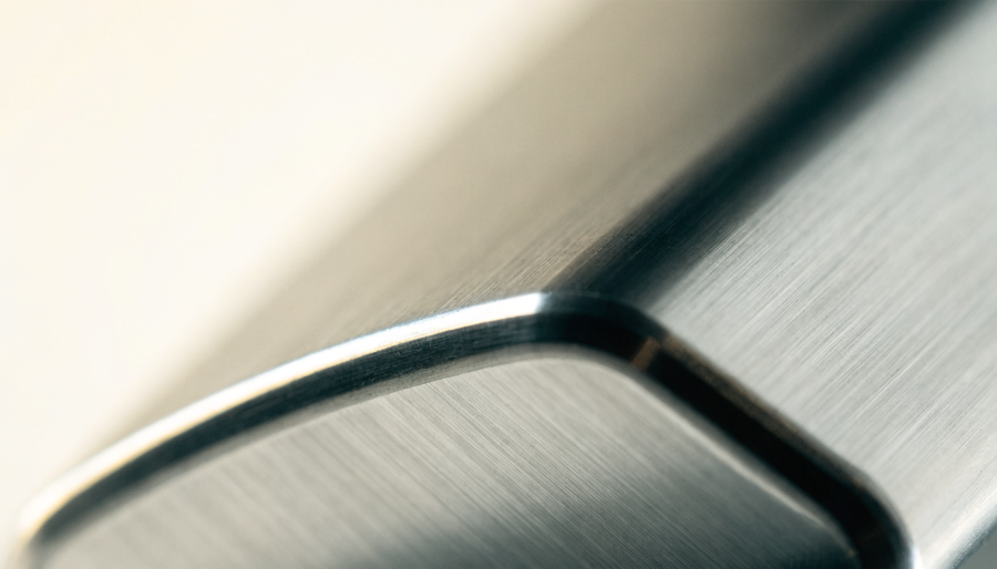Macro detail of a 45-degree chamfer catching light on a brushed aluminium edge